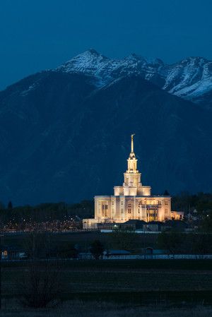 a large church lit up at night with mountains in the background