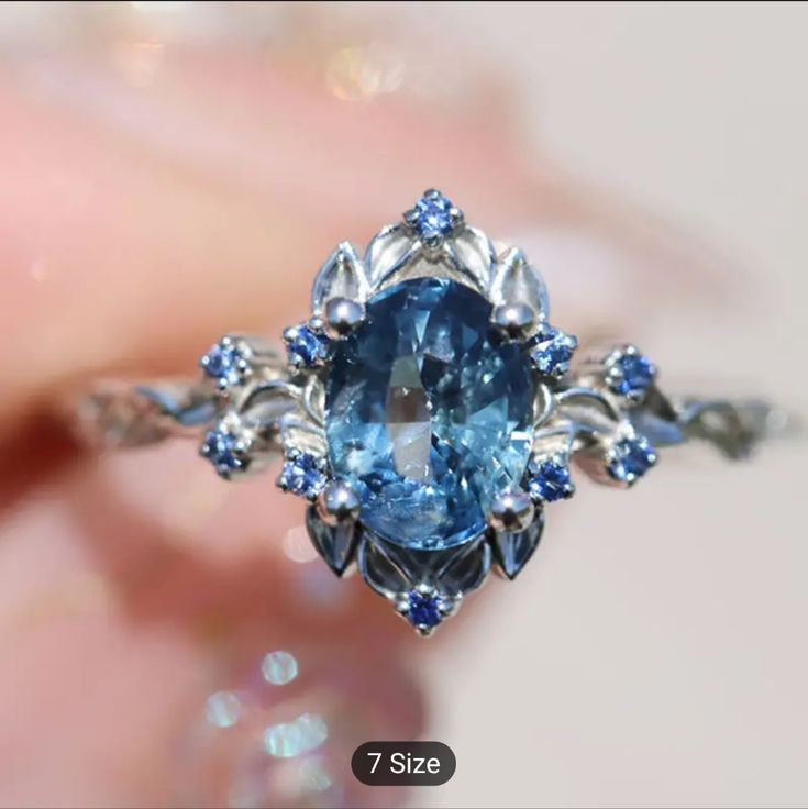 a close up of a ring with a blue stone in the center and diamonds around it