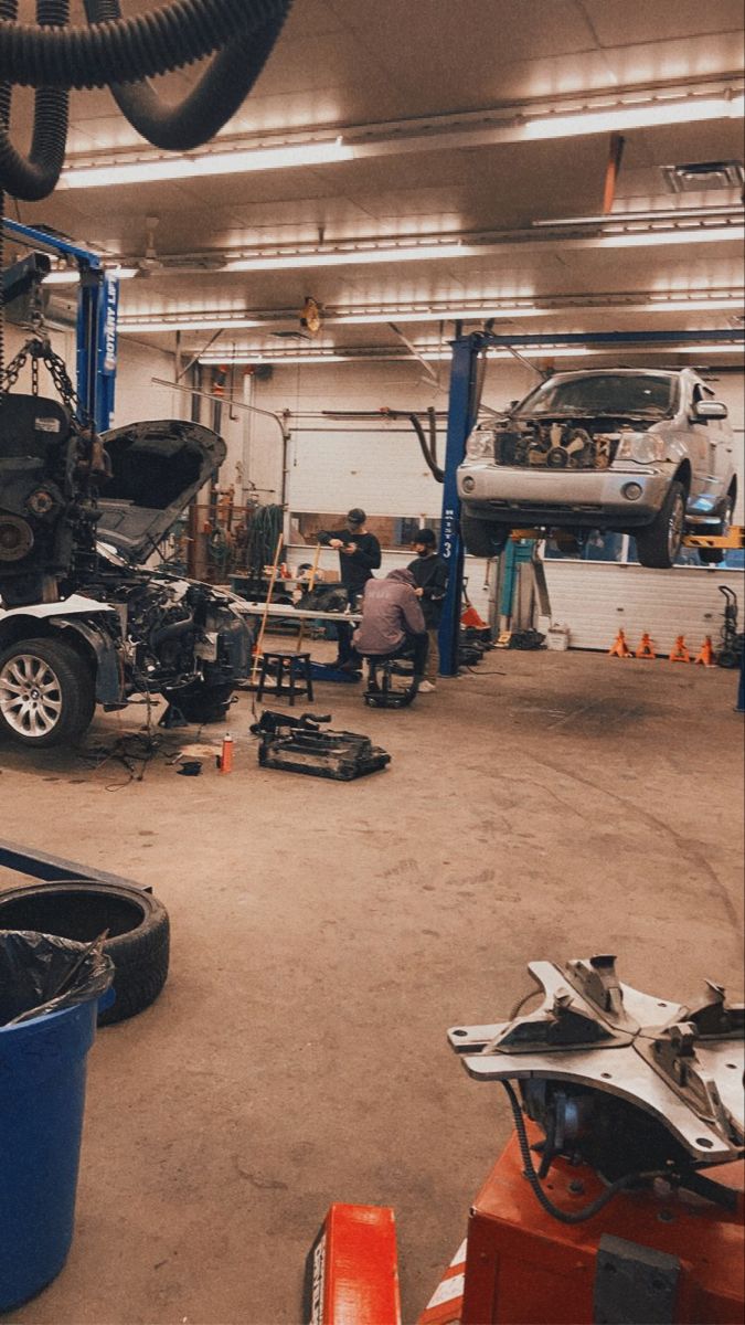 a garage filled with lots of cars and workers working on the car parts in it