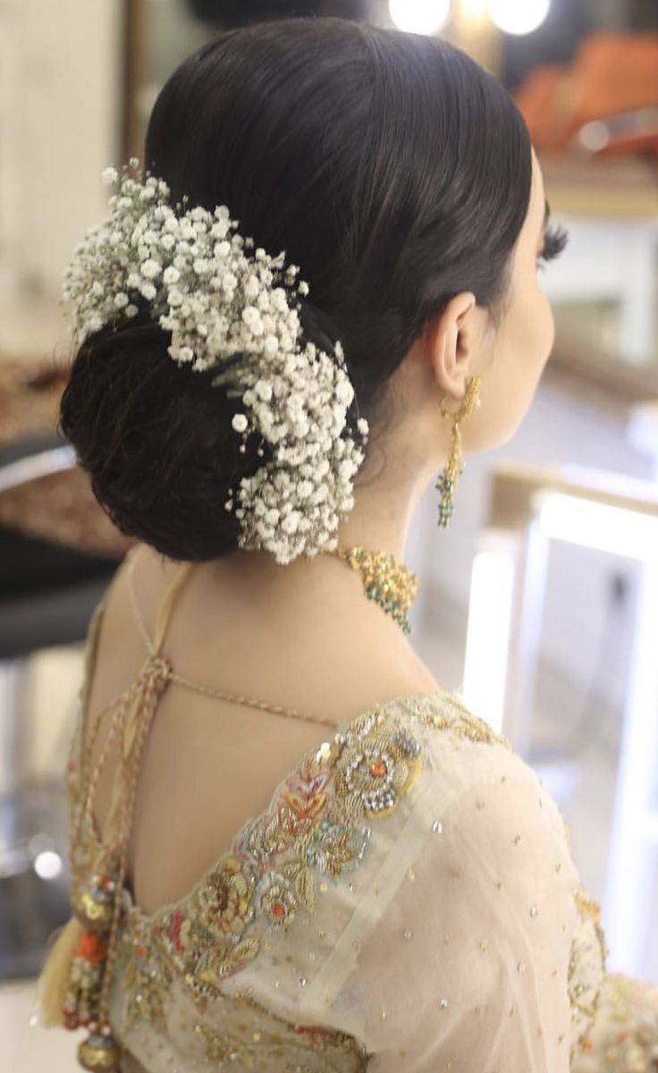 a woman in a white dress with flowers on her hair is looking at something off to the side