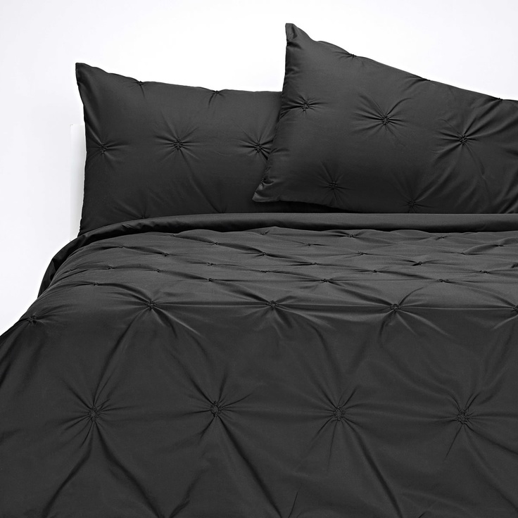 a bed with black sheets and pillows on it