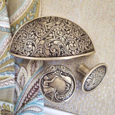 an ornate silver broochle with a horse on it's side and two matching knobs