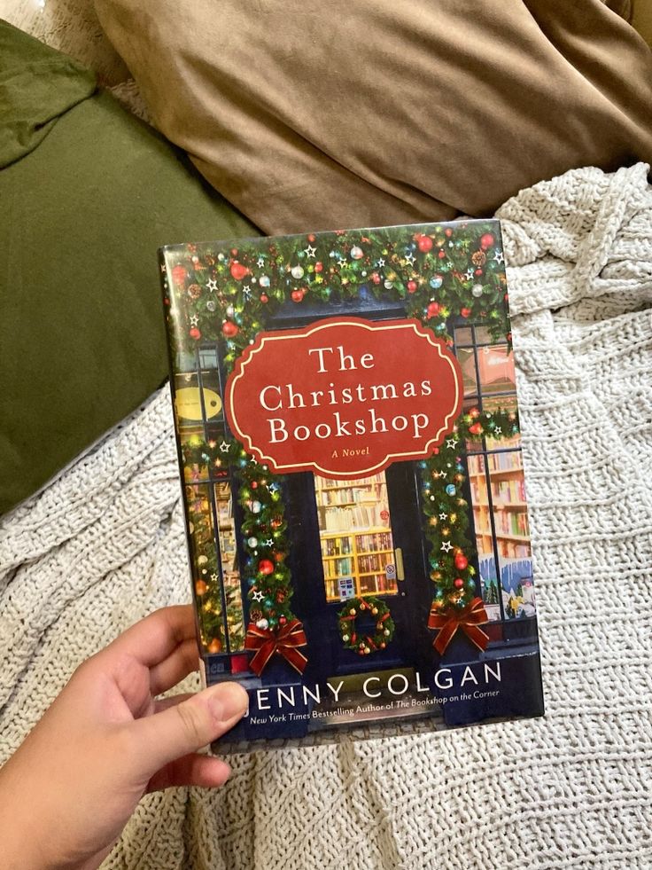 the christmas bookhop by jenny colgan is in someone's hand on a bed