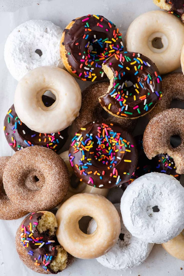 a bunch of doughnuts that are sitting on a white tablecloth with sprinkles