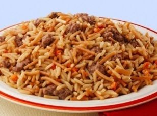 a white plate topped with rice and meat on top of a red and white table cloth