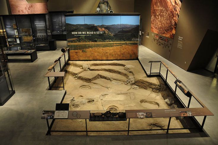 an exhibit with dirt and sand in it's display cases, including a dinosaur skeleton