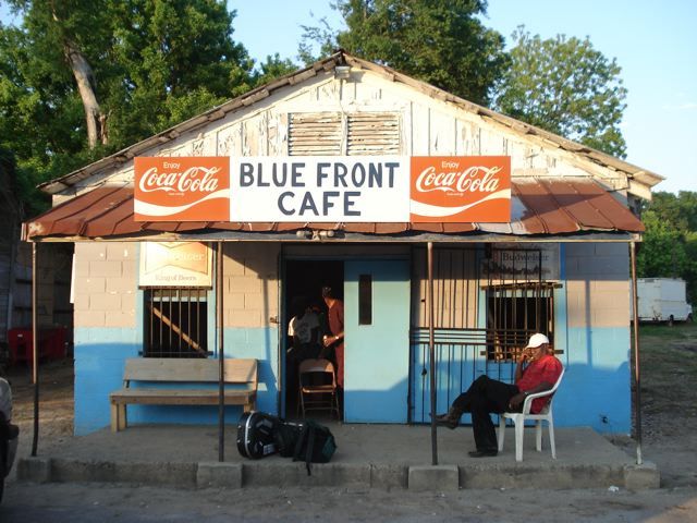 two people sitting in chairs outside of a blue front cafe