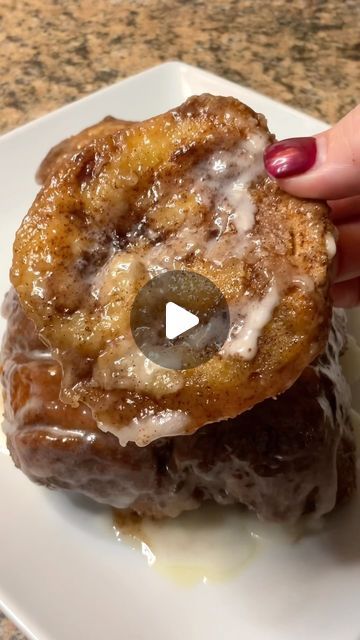 a person holding up a donut with icing on it