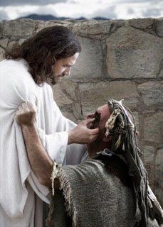 jesus with his hands on the head of a man in front of a stone wall