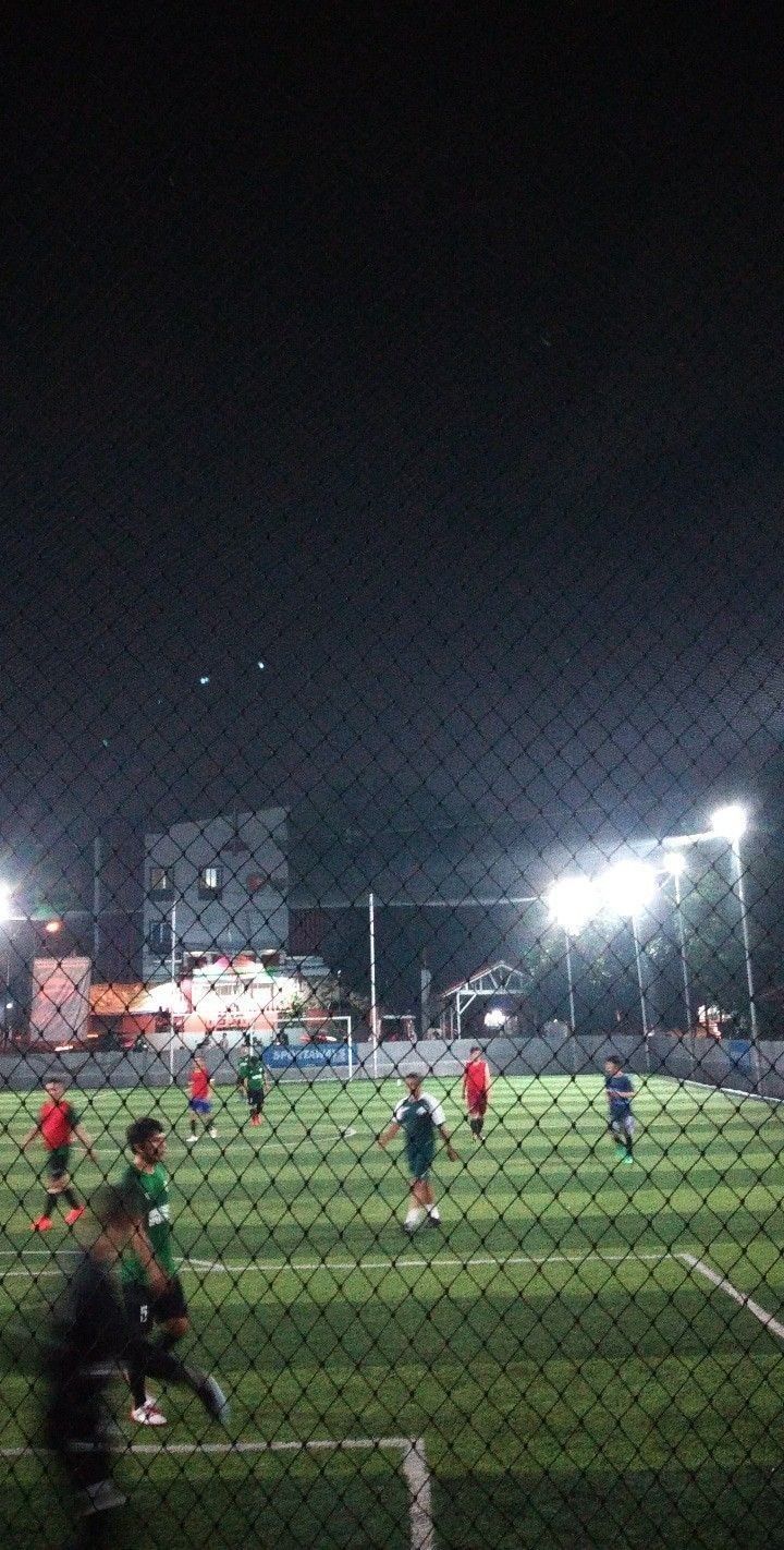 a group of people playing soccer on a field at night