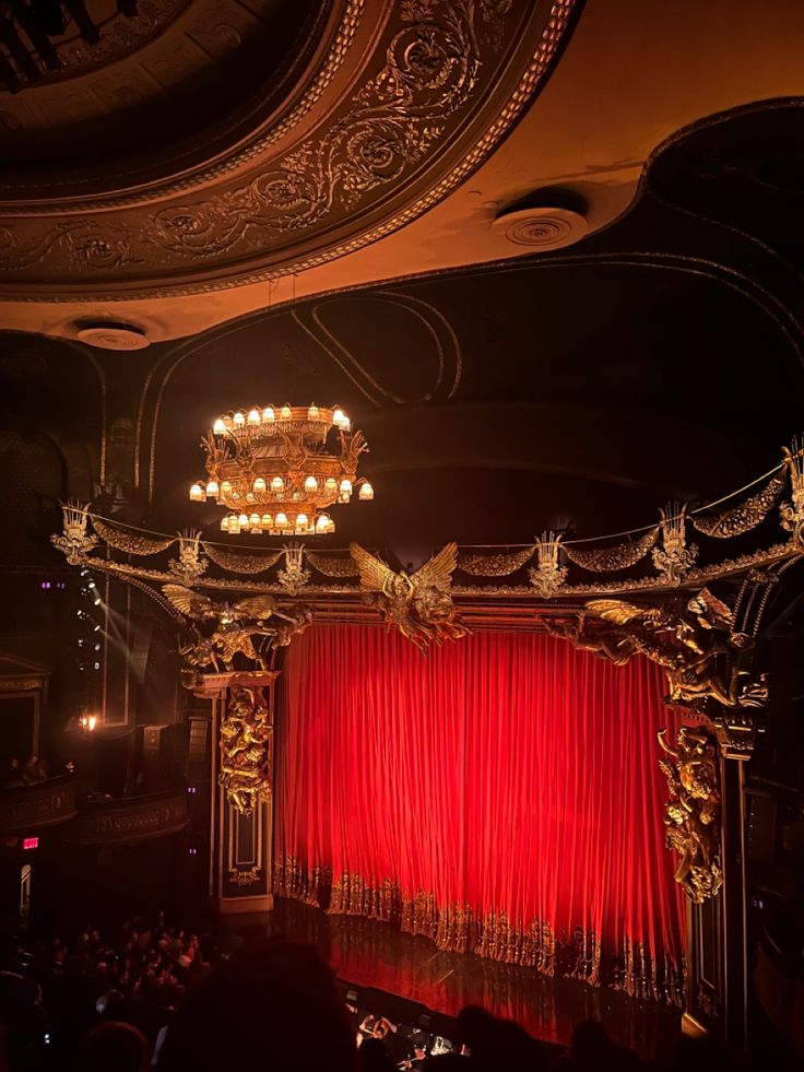 an ornate stage with red curtains and chandelier