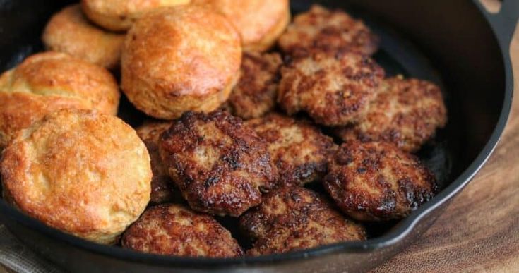 some food is in a black pan on a wooden table and ready to be eaten