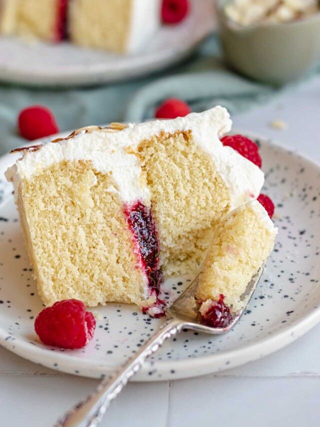 a piece of cake on a plate with raspberries