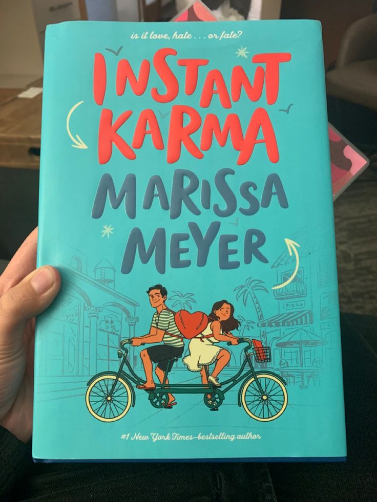 a person holding up a book in front of their face with the title i instant karma written on it