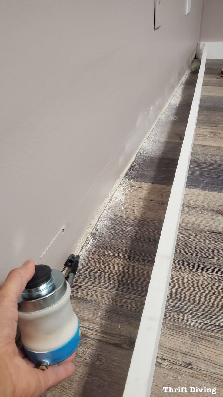 a person is using a spray bottle to paint the floor in a room with wood floors