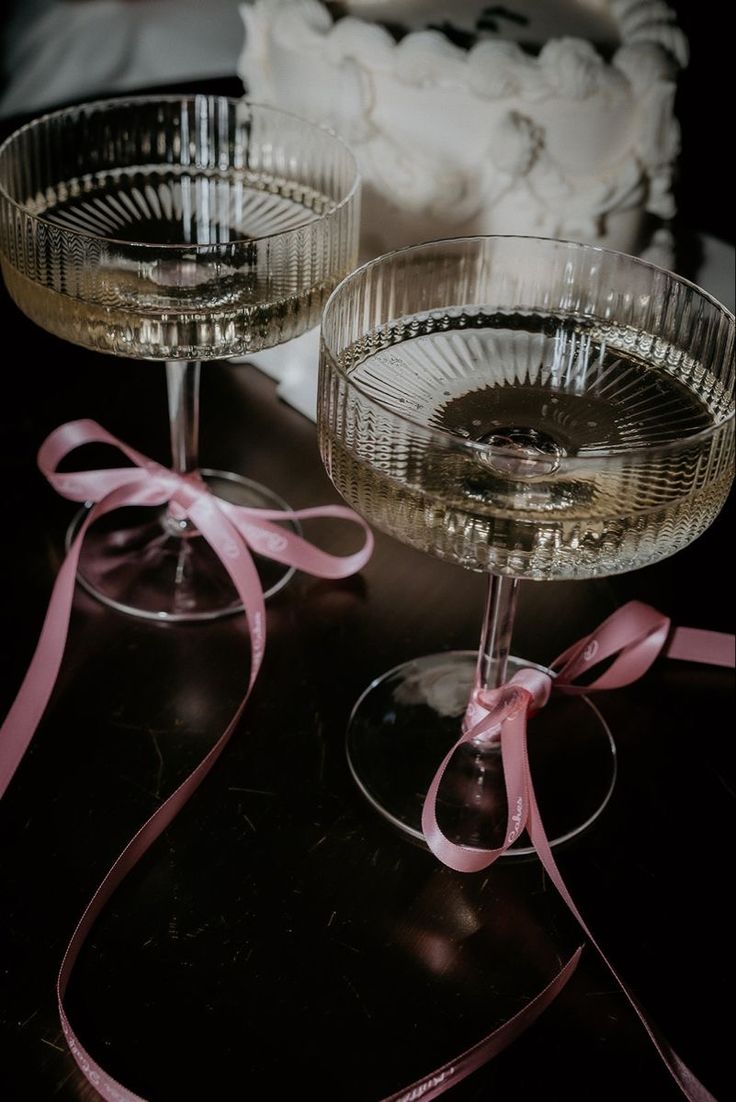 two wine glasses with pink ribbons on them