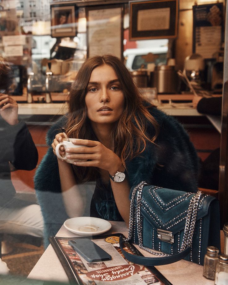 a woman sitting at a table holding a cup