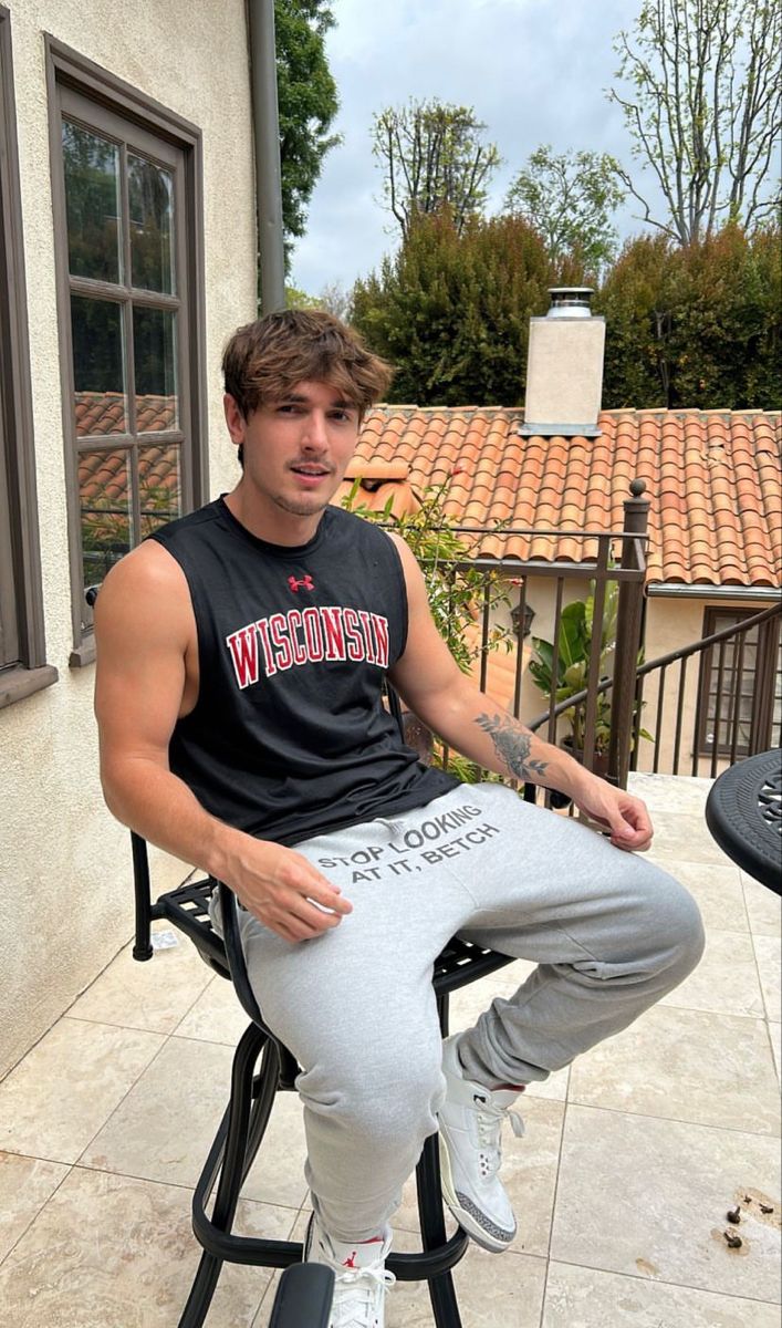 a young man sitting on top of a chair in front of a building with a basketball hoop