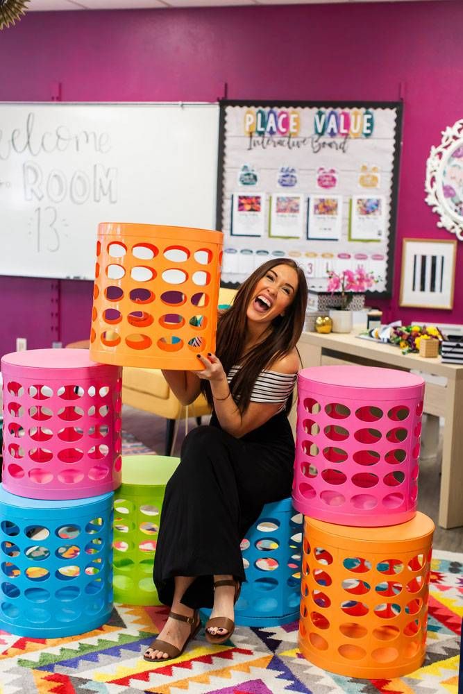 a woman sitting on top of a pile of colorful plastic stools in a room