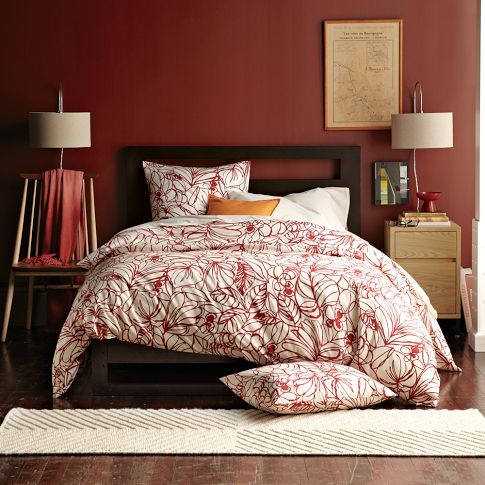 a bed in a room with red walls and wooden flooring on the other side