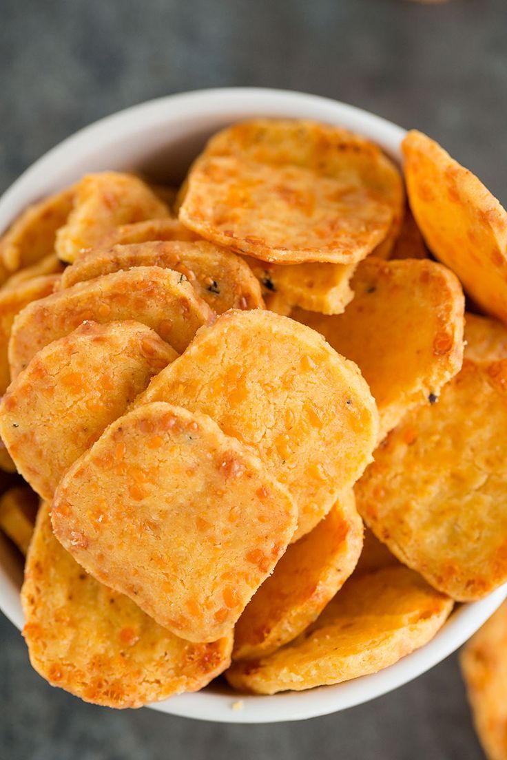 a white bowl filled with potato chips sitting on top of a gray countertop next to other food items