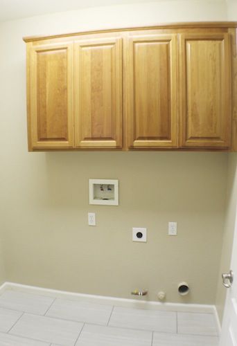 an empty bathroom with wooden cabinets above the toilet