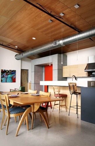 an open kitchen and dining room area with wood floors, white walls, and exposed ceilings