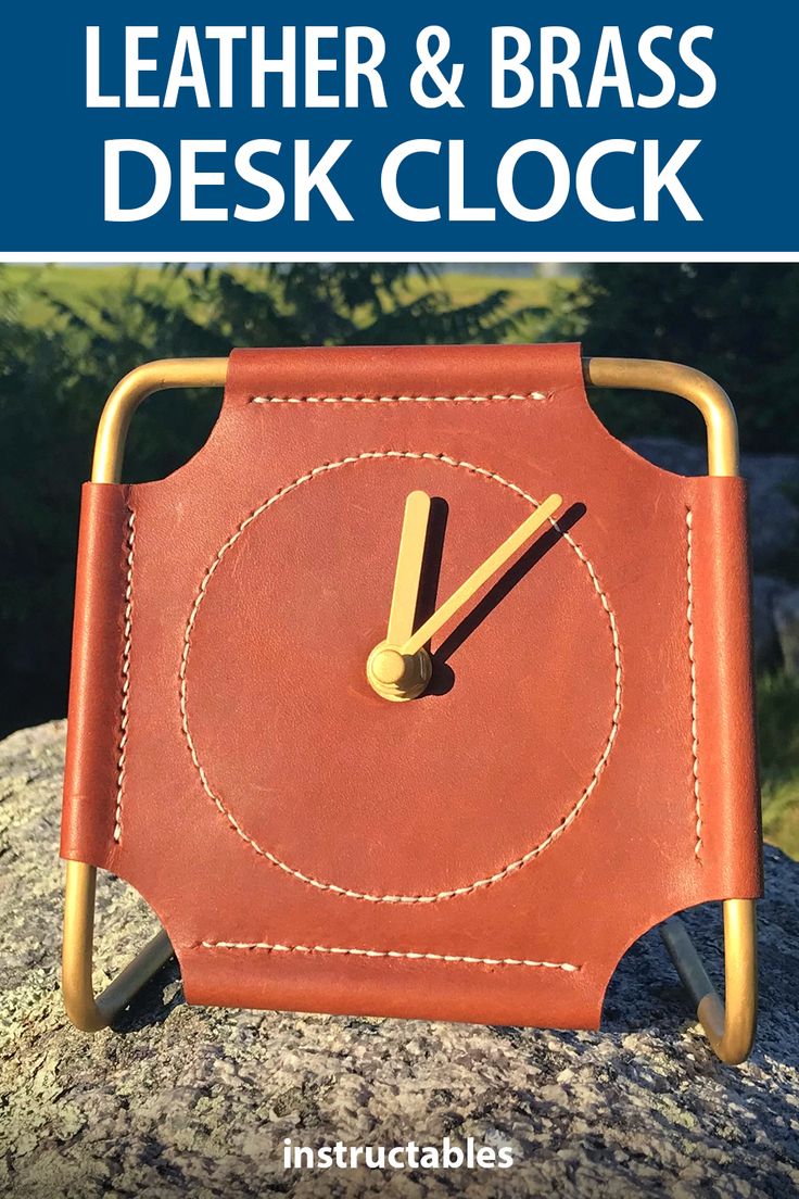 a leather and brass desk clock sitting on top of a rock with the words leather & brass desk clock