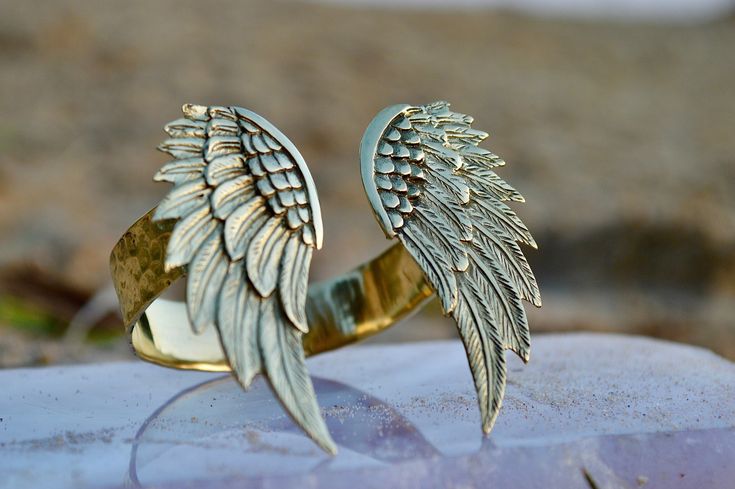 Introducing our exquisite Brass Angel-Wing Armbands, a symbol of elegance and grace that is sure to captivate any fashion-forward individual. Meticulously handcrafted using high-quality nickel-free brass, these armbands are not only stunning but also durable and long-lasting. The armbands feature intricately detailed angel wings that strike the perfect balance between striking and delicate. The unique design of the wings allows them to beautifully capture the light, casting a stunning radiance t Angel Wing Bracelet, Wedding Jewelry Earrings, The Wings, Timeless Jewelry, Wedding Earrings, Angel Wings, Earring Necklace, Arm Band, Handcrafted Jewelry