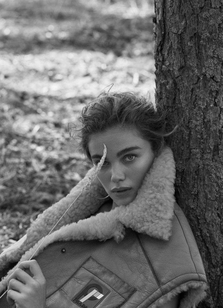 black and white photograph of a woman leaning against a tree with her nose covered by a scarf