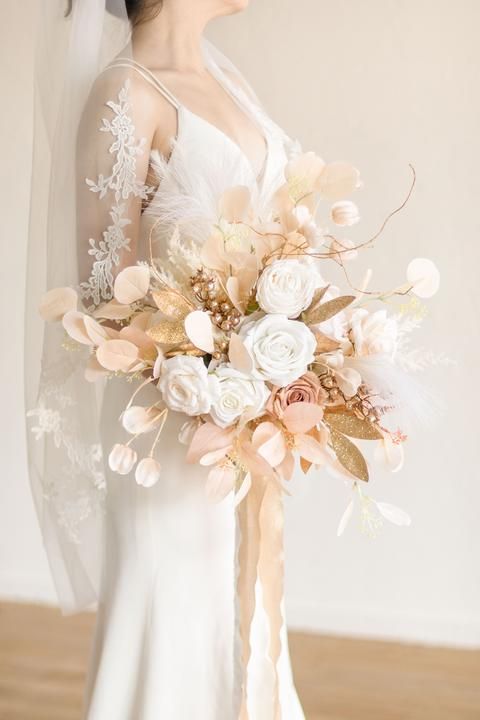 a woman in a wedding dress holding a bridal bouquet with flowers on the side