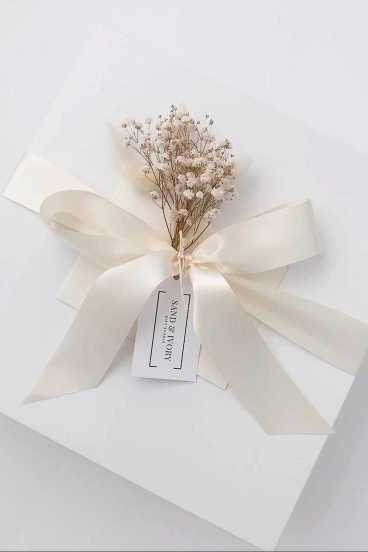 a bouquet of dried flowers tied to a white gift box with a tag on it