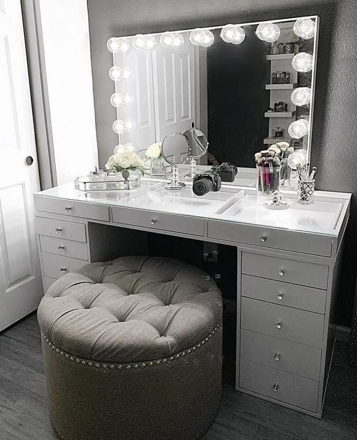 a vanity with stool, mirror and lights on it