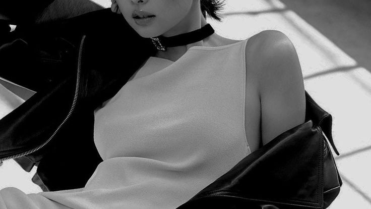 black and white photograph of a woman sitting on a chair with her hand in her purse