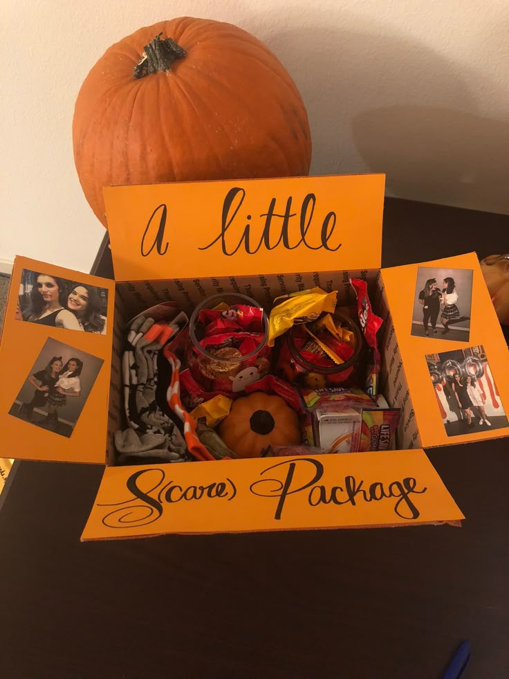 an orange box filled with halloween candies next to a pumpkin