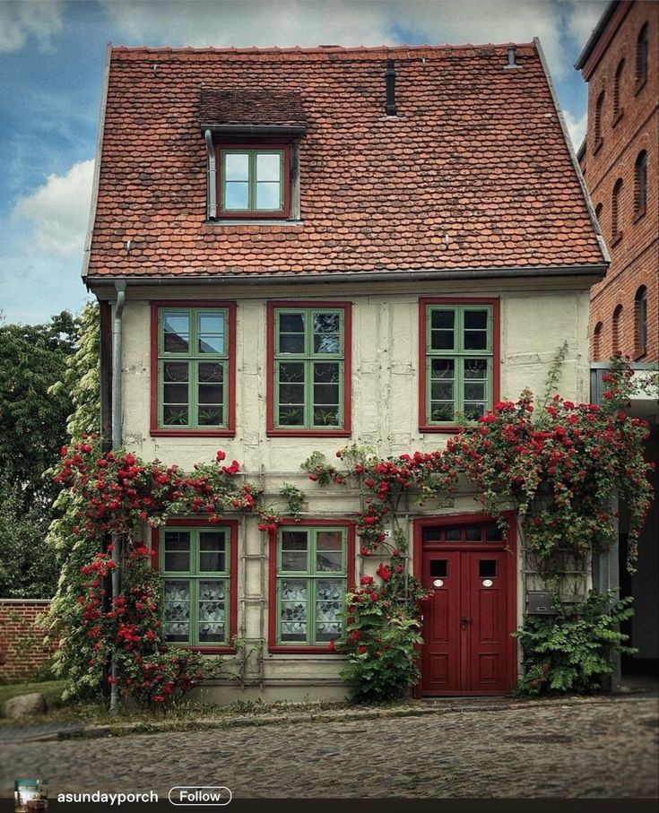 an old house with red flowers growing on it