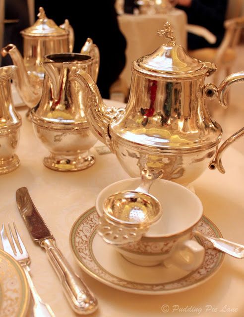 a silver tea set sitting on top of a table next to other silverware and utensils