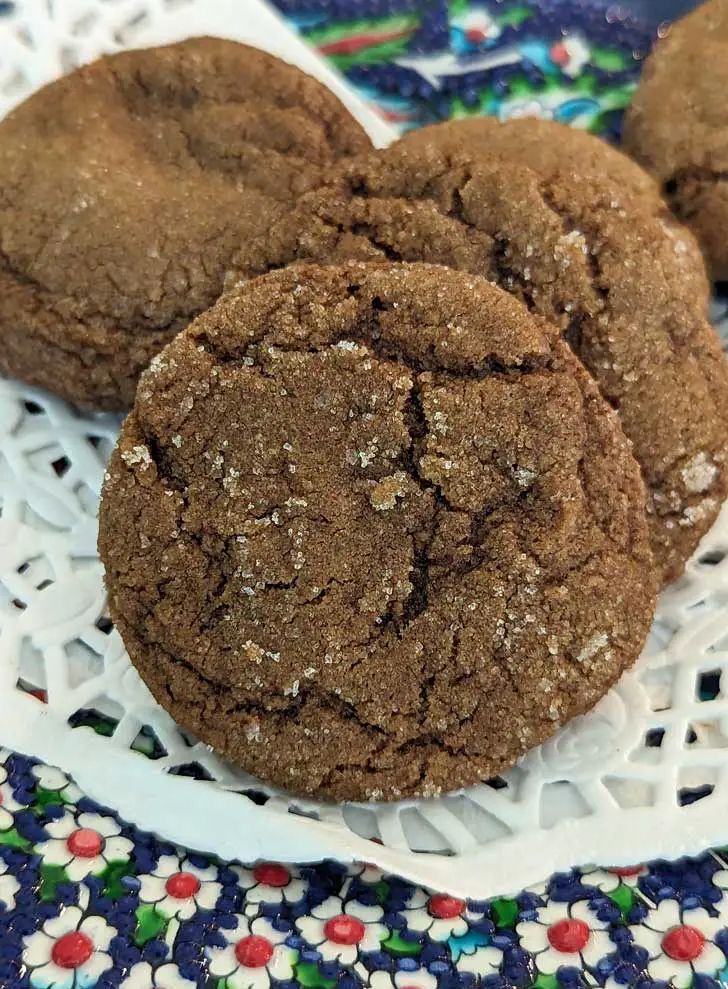 three chocolate cookies sitting on top of a white plate next to a blue and red flowered cloth