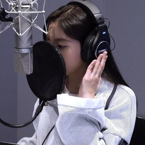 a young woman wearing headphones sitting in front of a microphone