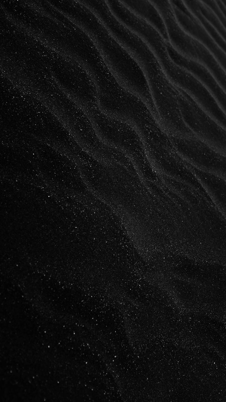 black sand dunes with small white dots in the middle and dark ground at the bottom