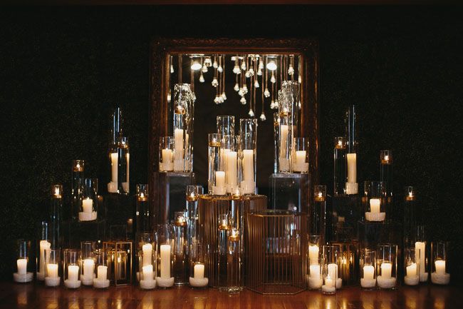 many candles are lit on the table in front of a mirror with an ornate frame