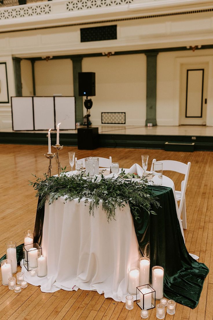 the table is set up with candles and greenery