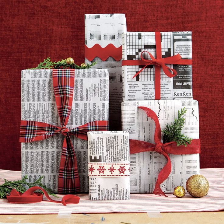 christmas presents wrapped in newspaper and tied with red ribbon, sitting on top of each other