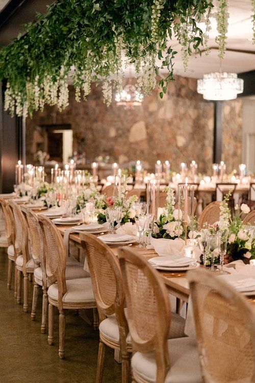 a long table with white flowers and greenery is set up for a formal function