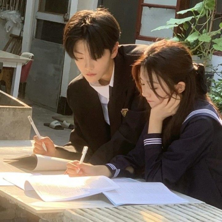 two people sitting at a table writing on paper