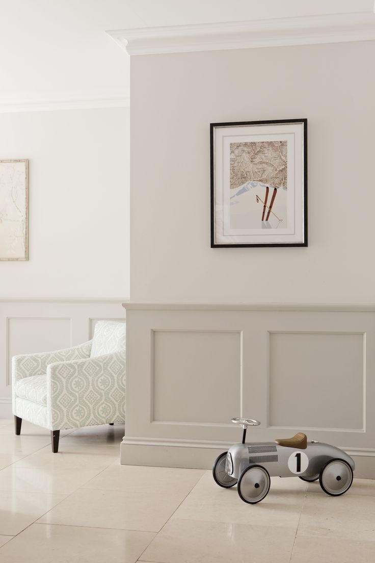 a toy bike sitting on top of a tiled floor next to a white chair and wall