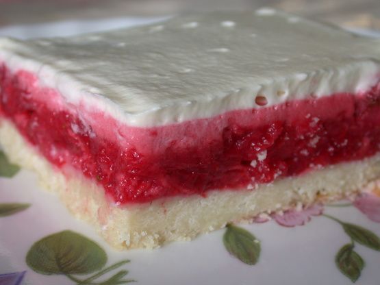 a piece of cake with white frosting and raspberry filling on a plate