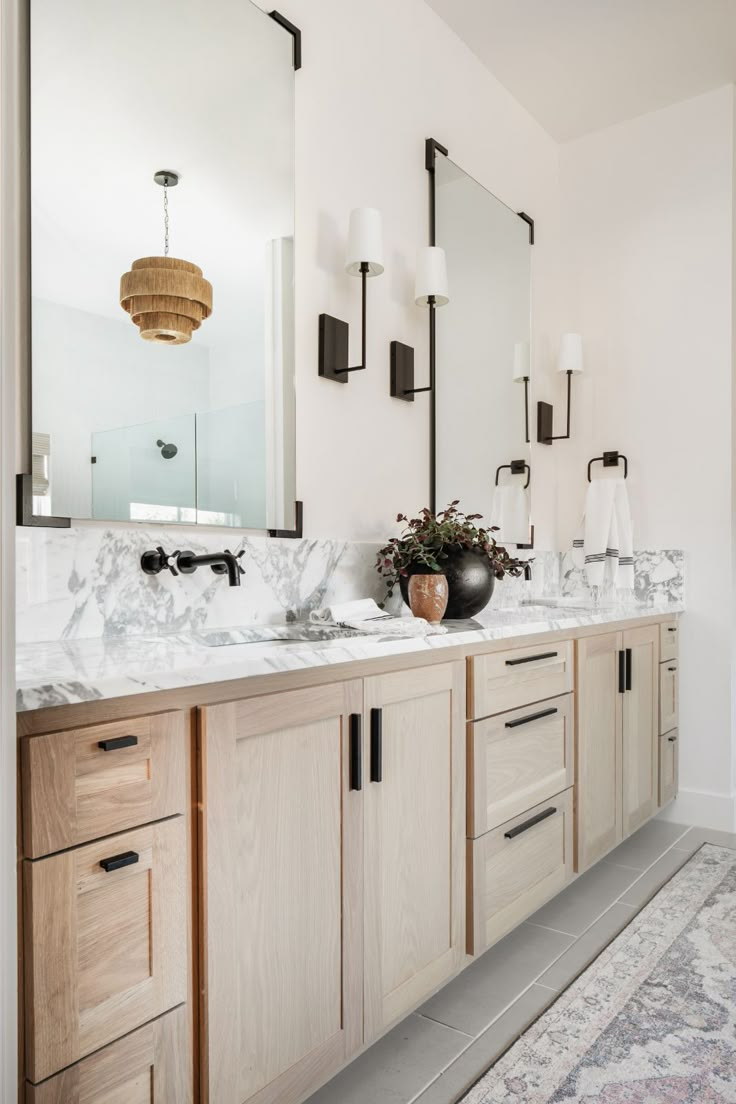 a bathroom with two sinks, mirrors and lights on the wall next to each other