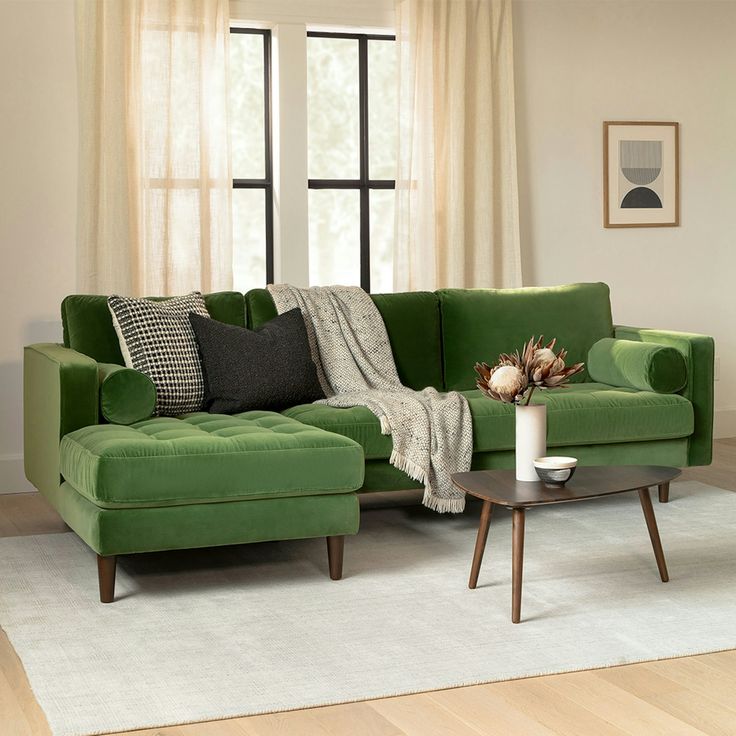 a living room with a green couch and coffee table in front of a large window