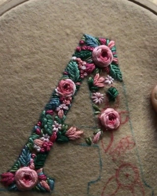 someone is stitching the letters with flowers